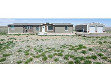 View of the front exterior of the home with a large yard and detached garage at 62681 E Hampden Pl, Byers, CO 80103