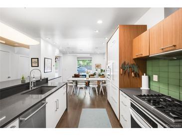 Bright kitchen featuring stainless steel appliances, dark countertops, and dining area with plenty of natural light at 1718 W 33Rd Ave, Denver, CO 80211