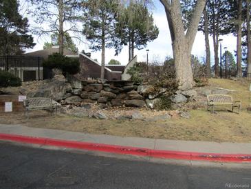 Landscaped exterior featuring stone accents, decorative benches, and mature trees enhance the property's curb appeal at 9725 E Harvard Ave # 346, Denver, CO 80231