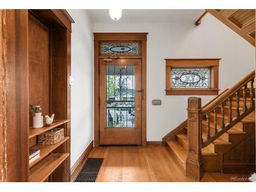 Charming foyer with hardwood floors, built-in shelving, and stained glass window accents by the front door and staircase at 3905 Tejon St, Denver, CO 80211