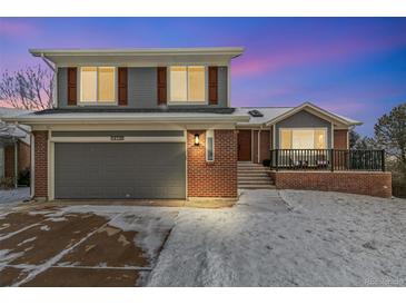 Two-story home with brick and gray siding, two car garage, and snow-covered front yard at 14126 W Harvard Pl, Lakewood, CO 80228