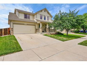 Charming two-story home with a well-maintained lawn, covered porch, attached two-car garage and concrete driveway at 11285 Iola St, Commerce City, CO 80640