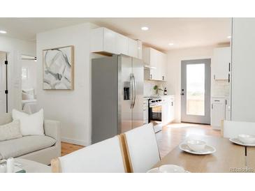 Bright, open kitchen featuring white cabinets, stainless steel appliances, and hardwood floors at 930 S Lowell Blvd, Denver, CO 80219