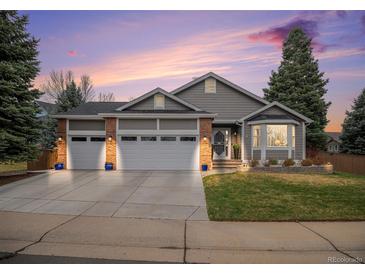 Charming home featuring a three car garage, well-manicured lawn, and attractive brick and siding details at 9705 Westbury Cir, Highlands Ranch, CO 80129