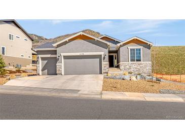 Charming single-Gathering home featuring a three-car garage, stone accents, and xeriscaped front yard at 4706 Mesa Top Dr, Monument, CO 80132
