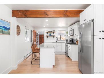 Bright kitchen featuring white cabinetry, stainless appliances, butcher block island, and a wooden beam at 3521 W 40Th Ave, Denver, CO 80211
