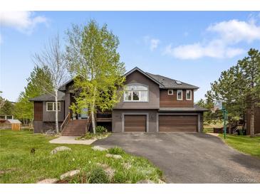 Two-story house with a two-car garage, natural landscaping, and a basketball hoop at 1654 Muirfield Ln, Evergreen, CO 80439