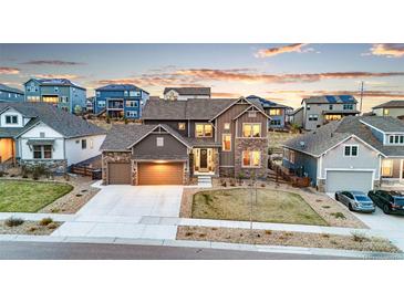 Beautiful two-story home with stone accents, a well-maintained lawn, and a two-car garage in a modern neighborhood at 18267 W 95Th Ave, Arvada, CO 80007