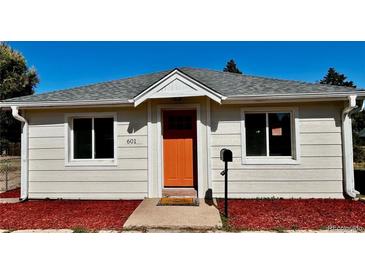 Charming home exterior featuring a bright orange front door and manicured landscaping at 601 W Layton Ave, Englewood, CO 80110