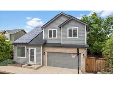 Charming two-story home featuring a grey exterior, solar panels, and a basketball hoop on the driveway at 1551 Northridge Dr, Highlands Ranch, CO 80126