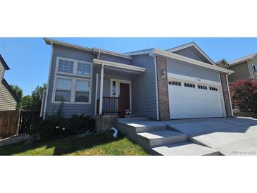 Charming home with gray siding, brick accents, attached garage, and well-maintained front yard at 12388 Jasmine St, Brighton, CO 80602