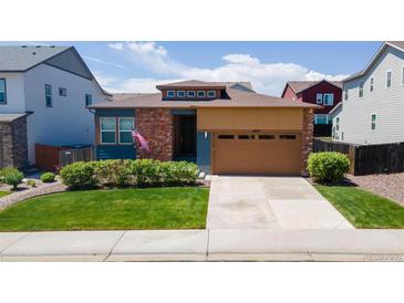 Inviting single-story home featuring a manicured lawn, brick accents, and a two-car garage at 6932 E 133Rd Ave, Thornton, CO 80602
