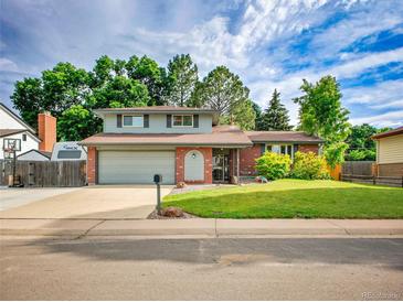 Charming two-story home with a lush green lawn, brick accents, and an attached two-car garage at 4720 W Stanford Ave, Denver, CO 80236