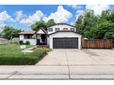 Charming two-story home featuring a two-car garage, manicured lawn, and inviting front porch at 8249 Zephyr St, Arvada, CO 80005