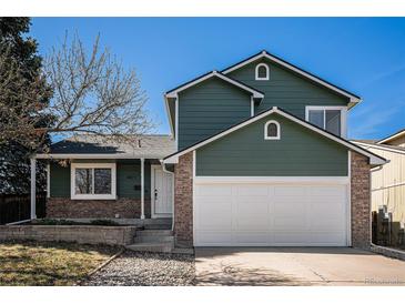 Two story home featuring a two car garage, green siding, brick accents, and manicured front yard at 4871 S Dunkirk Way, Centennial, CO 80015