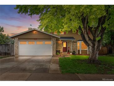 Charming two-story home featuring a brick and wood facade, mature tree, and a two-car garage at 10450 Iris Way, Broomfield, CO 80021