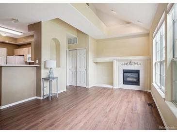 Bright living room featuring a fireplace, vaulted ceilings, and large windows for natural light at 8371 S Upham Way # 103, Littleton, CO 80128