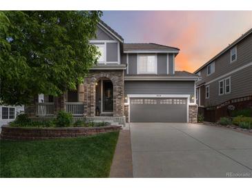 Charming two-story home featuring a brick facade, covered porch and manicured lawn, showcasing curb appeal at 2828 Shadow Dance Dr, Castle Rock, CO 80109