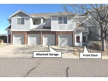 Charming townhome featuring a front door, attached garage, and manicured landscaping at 10259 W 55Th Dr # 103, Arvada, CO 80002