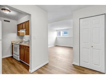 An open floor plan showcases the kitchen with white appliances and wood floors throughout at 3613 S Sheridan Blvd # 7, Denver, CO 80235