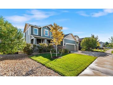 Charming two-story home featuring a well-manicured lawn, mature tree, and an attached two-car garage at 6310 S Ider St, Aurora, CO 80016