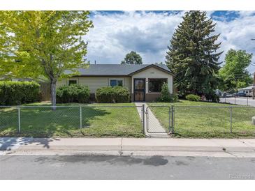 Charming single-story home with chain fence, manicured lawn, and mature trees at 1099 Wheeling St, Aurora, CO 80011