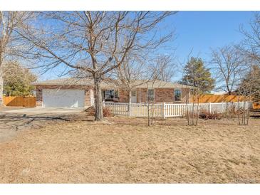 Charming single story home with brick exterior, attached two-car garage, and white picket fence at 2372 Haskell Way, Watkins, CO 80137