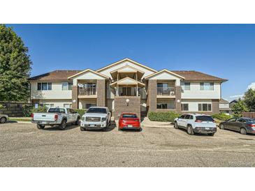 Apartment complex exterior featuring brick accents, balconies, and ample parking spaces at 875 E 78Th Ave # 9-2, Denver, CO 80229