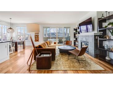 Bright living room boasts hardwood floors, fireplace, built-ins, and access to a private balcony at 111 S Monroe St # B203, Denver, CO 80209