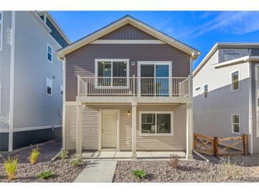 Two-story townhome with balcony, light beige and brown siding, and small front yard at 45036 Sunflower Ln, Bennett, CO 80102