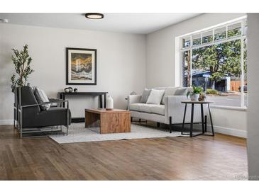 Bright living room featuring hardwood floors, modern furniture, and a large window with a neighborhood view at 6923 S Albion St, Centennial, CO 80122