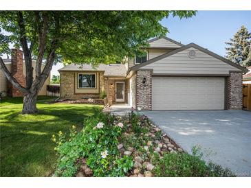 Charming two-story home with a well-manicured lawn and a lovely flower garden in front at 17657 E Prentice Cir, Aurora, CO 80015