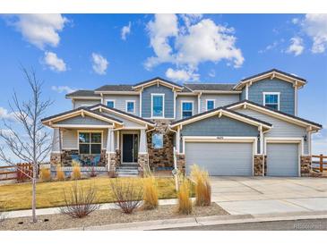 Two-story home with a stone and siding exterior, three-car garage, covered porch, and well-manicured front lawn at 16272 W 95Th Ln, Arvada, CO 80007