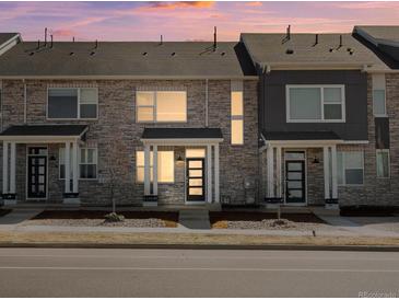 Charming townhouse boasts a stylish stone facade and modern design elements with a colorful sky at 22360 E 8Th Ave, Aurora, CO 80018