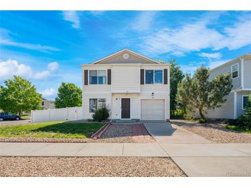 Well-maintained home featuring a tidy front yard, attached garage, and inviting entrance, showcasing a blend of comfort and curb appeal at 4528 Andes St, Denver, CO 80249