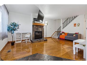 Bright living room with hardwood floors, fireplace and flatscreen TV, leading to carpeted stairs with black railing at 3355 Talisman Ct # C, Boulder, CO 80301