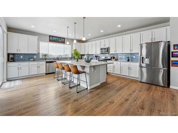 Bright kitchen featuring white cabinets, stainless steel appliances, and a large center island with seating at 11744 Magnolia Dr, Thornton, CO 80233