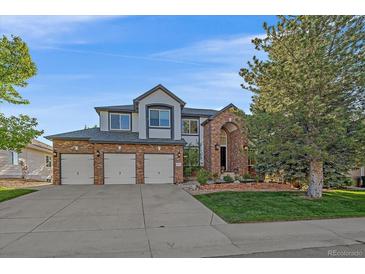 Inviting brick home boasts a three-car garage and beautifully landscaped front yard at 10125 Quarry Hill Pl, Parker, CO 80134