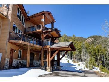 A three story home has a wooden exterior with a stone foundation and multiple covered decks at 10508 Christopher Dr, Conifer, CO 80433