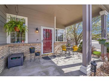 Charming front porch with seating area, potted plants, and a welcoming red door at 19447 E Bellisario Creek Dr, Parker, CO 80134