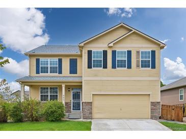 Charming two-story home featuring a 2-car garage, covered porch, and manicured lawn at 443 Hermosa St, Brighton, CO 80603