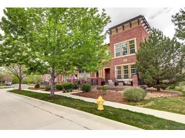 Inviting brick townhome with a manicured lawn and mature trees lining the sidewalk at 800 Rockhurst Dr # D, Highlands Ranch, CO 80129