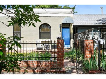 Charming home exterior featuring a blue front door, brick fence, and well-maintained landscaping at 361 Elati St, Denver, CO 80223