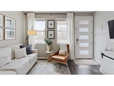 Cozy living room featuring a comfortable couch, stylish decor, and ample natural light from large windows at 21823 E 8Th Ave, Aurora, CO 80018