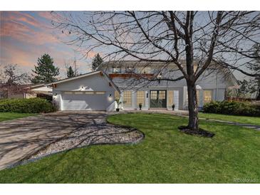 Charming two-story home featuring a well-manicured lawn, mature landscaping, and an attached garage at 5467 W Hinsdale Pl, Littleton, CO 80128