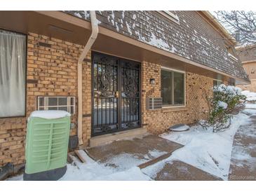 Brick exterior with a decorative wrought iron storm door and snow on the ground at 1759 Quail St, Lakewood, CO 80215