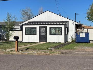 Charming white home with a black door and decorative windows, complemented by a well-maintained green lawn at 1910 Altura Blvd, Aurora, CO 80011