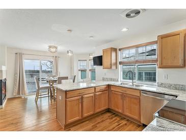 Bright kitchen with wood floors, stainless appliances, granite counters, and an adjacent dining area at 24285 E Wagon Trail Ave, Aurora, CO 80016