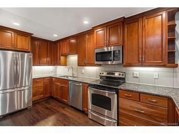 Modern kitchen features stainless steel appliances, granite countertops, and warm wood cabinetry at 9315 E Center Ave # 3D, Denver, CO 80247