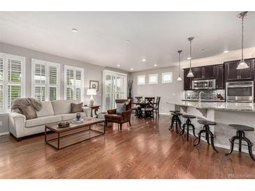 Bright, open-concept living area flows into kitchen and dining, with hardwood floors and plantation shutters at 7991 Heritage Dr, Thornton, CO 80602